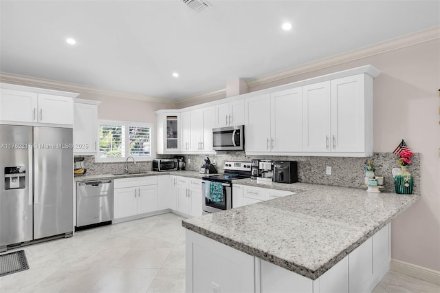 kitchen featuring a peninsula, crown molding, appliances with stainless steel finishes, and a sink