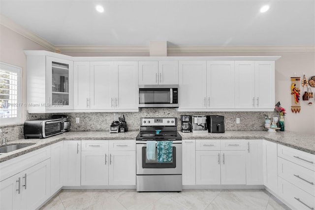 kitchen with decorative backsplash, white cabinets, stainless steel appliances, and ornamental molding