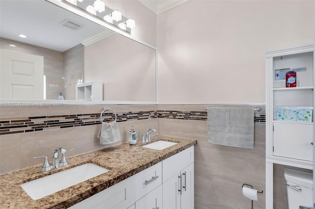 full bathroom with double vanity, toilet, visible vents, and a sink