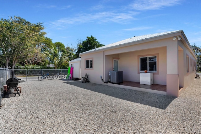 rear view of property with fence, stucco siding, cooling unit, metal roof, and a patio area