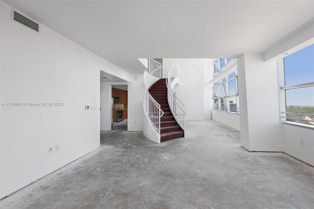 unfurnished living room with visible vents, stairway, and concrete floors