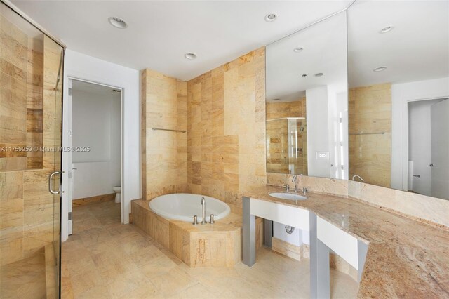 bathroom featuring toilet, a garden tub, recessed lighting, a stall shower, and a sink