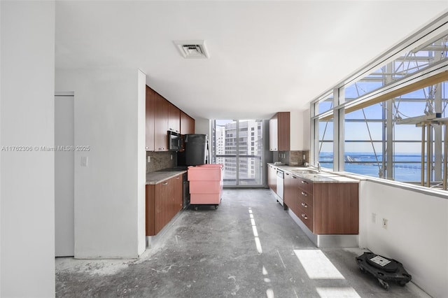 kitchen with visible vents, stainless steel microwave, tasteful backsplash, white dishwasher, and concrete flooring