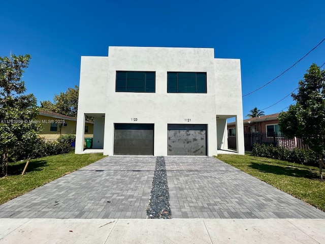 1121 NW 25th St, Miami, FL 33127 - modern home with stucco siding, an attached garage, decorative driveway, and a front lawn