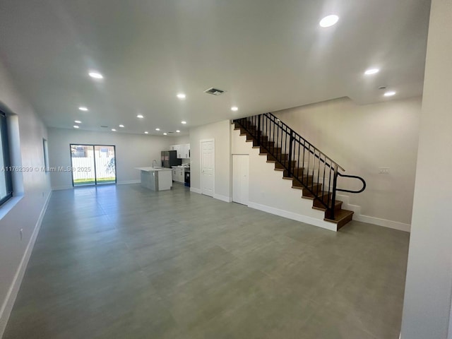 unfurnished living room with recessed lighting, visible vents, baseboards, and stairs