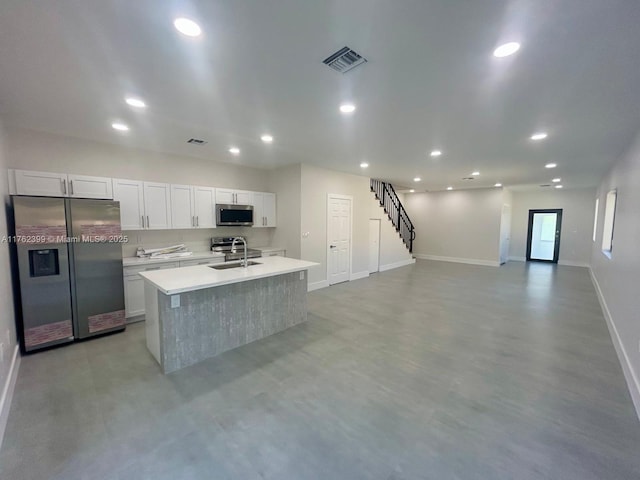 kitchen featuring visible vents, an island with sink, stainless steel appliances, light countertops, and white cabinetry