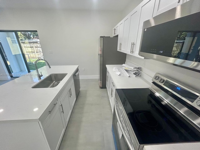 kitchen with a center island with sink, light countertops, appliances with stainless steel finishes, white cabinetry, and a sink