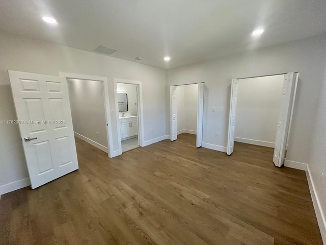 unfurnished bedroom with recessed lighting, baseboards, two closets, and wood finished floors