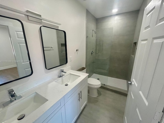 full bathroom featuring double vanity, a stall shower, toilet, and a sink