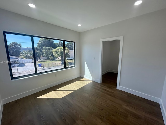 spare room with recessed lighting, baseboards, and dark wood-style floors