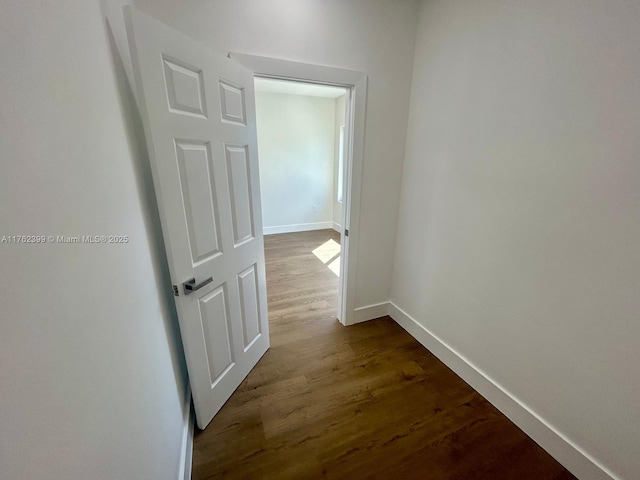 hallway featuring dark wood-type flooring and baseboards