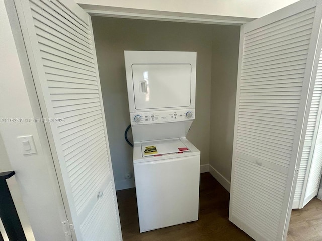 washroom with laundry area, baseboards, dark wood-type flooring, and stacked washing maching and dryer