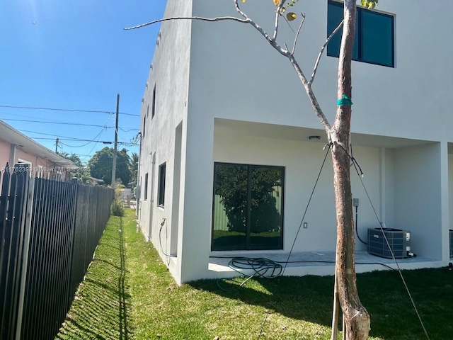 view of side of home featuring cooling unit, fence, and stucco siding