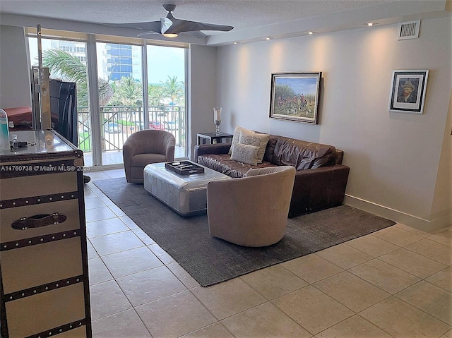 living room featuring visible vents, a textured ceiling, light tile patterned flooring, baseboards, and ceiling fan