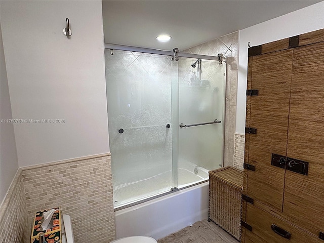 bathroom featuring shower / bath combination with glass door and tile walls