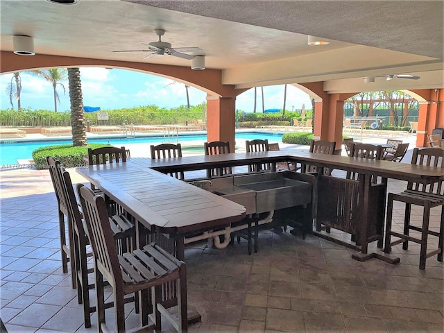 view of patio / terrace featuring outdoor dining area, a ceiling fan, and a community pool