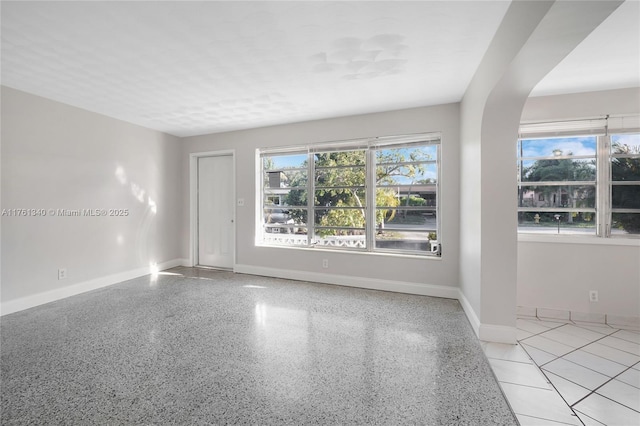 empty room featuring speckled floor and baseboards