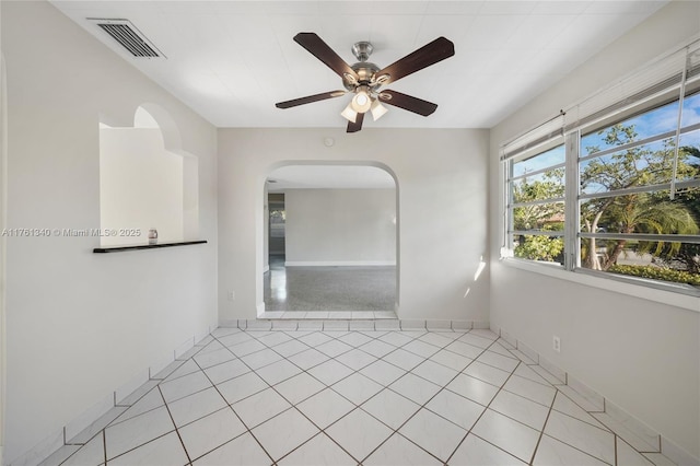 spare room with a ceiling fan, light tile patterned flooring, baseboards, and visible vents