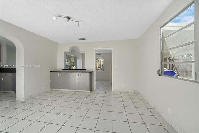 unfurnished room featuring light tile patterned flooring, visible vents, and baseboards