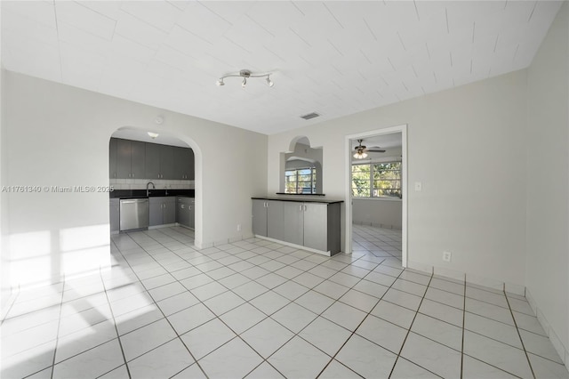 spare room featuring light tile patterned floors, arched walkways, visible vents, and baseboards