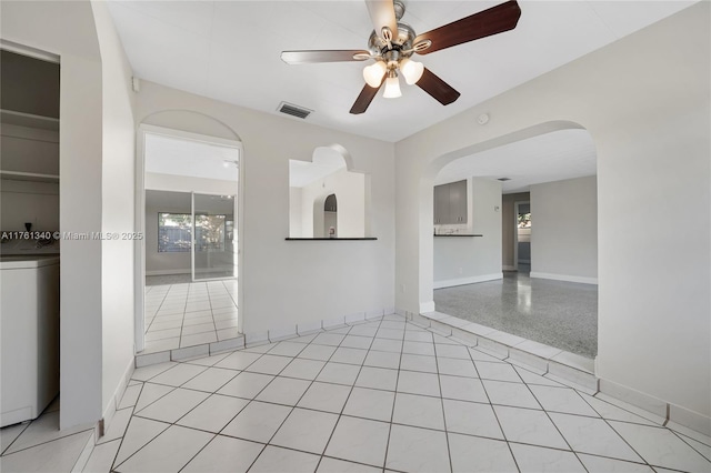 unfurnished room featuring visible vents, baseboards, ceiling fan, washer / dryer, and light tile patterned flooring