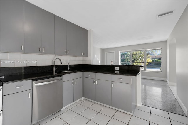 kitchen with visible vents, a peninsula, a sink, stainless steel dishwasher, and tasteful backsplash