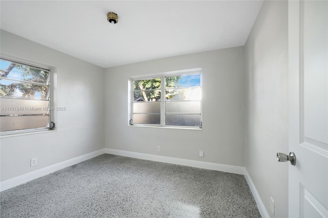 spare room with speckled floor and baseboards