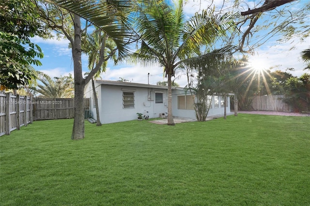 back of house with a yard, a fenced backyard, and stucco siding