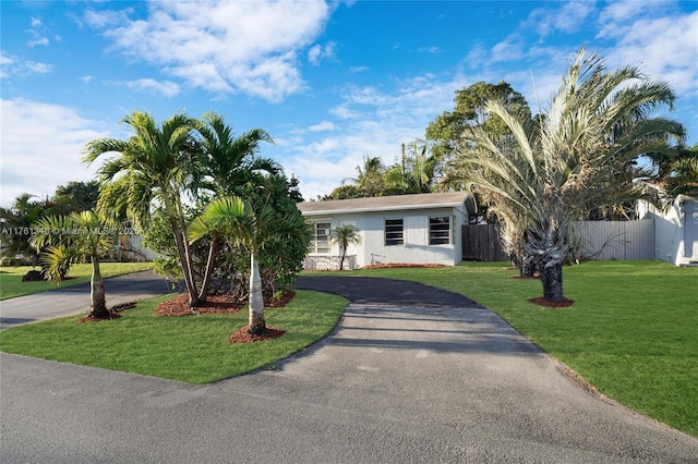 ranch-style house with a front lawn, fence, driveway, and stucco siding