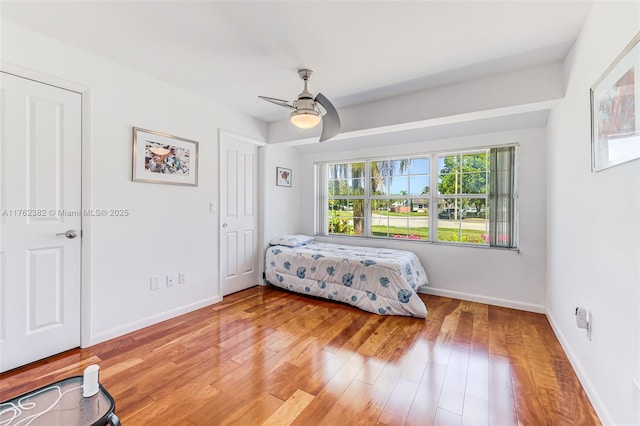 bedroom with baseboards, light wood-style floors, and a ceiling fan