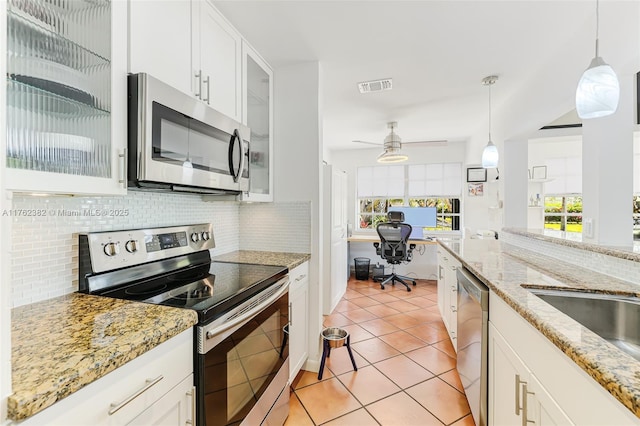 kitchen with visible vents, stainless steel appliances, white cabinets, built in study area, and hanging light fixtures