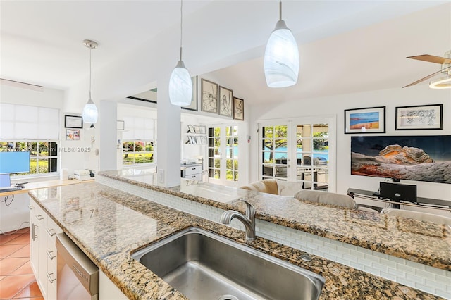 kitchen featuring a healthy amount of sunlight, light tile patterned flooring, a sink, dishwasher, and open floor plan