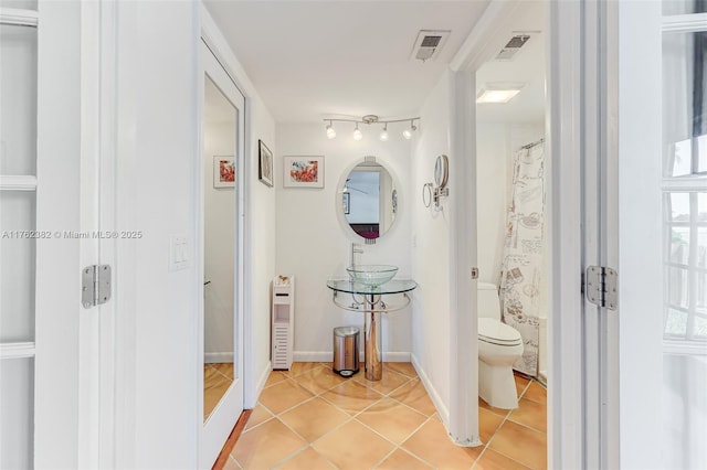 bathroom featuring tile patterned floors, visible vents, baseboards, and toilet