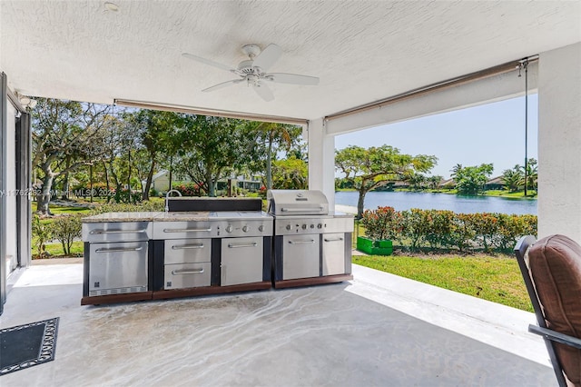 view of patio with ceiling fan, a water view, exterior kitchen, a grill, and a sink