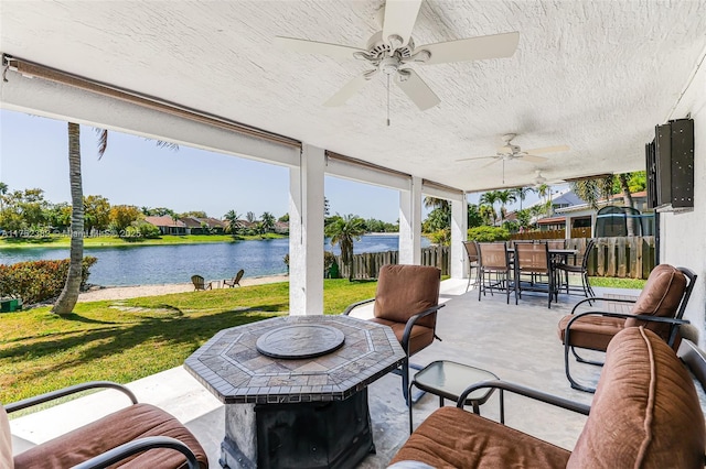 view of patio featuring outdoor dining space, fence, a ceiling fan, and a water view