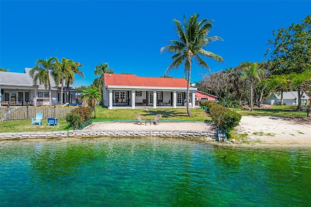 back of property featuring a patio, a lawn, fence, and a water view