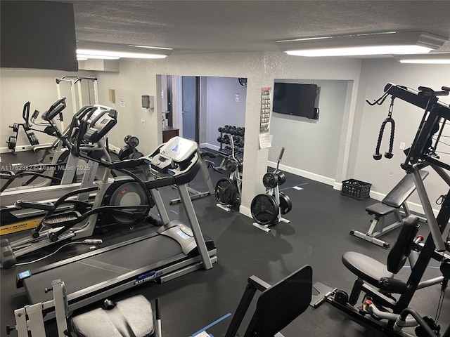 exercise room with a textured ceiling and baseboards