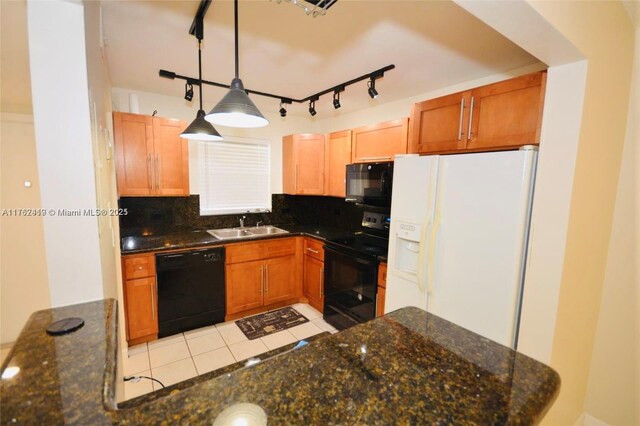 kitchen with decorative backsplash, dark stone countertops, hanging light fixtures, black appliances, and a sink