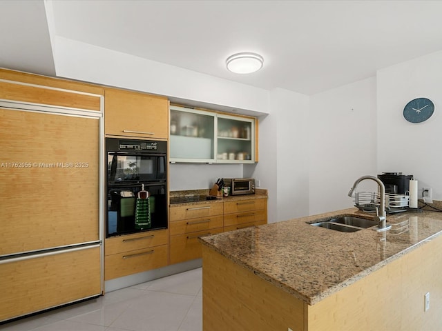 kitchen with stone counters, a sink, dobule oven black, a peninsula, and light tile patterned floors