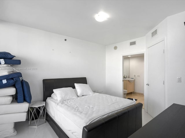 bedroom featuring ensuite bathroom, visible vents, and a sink