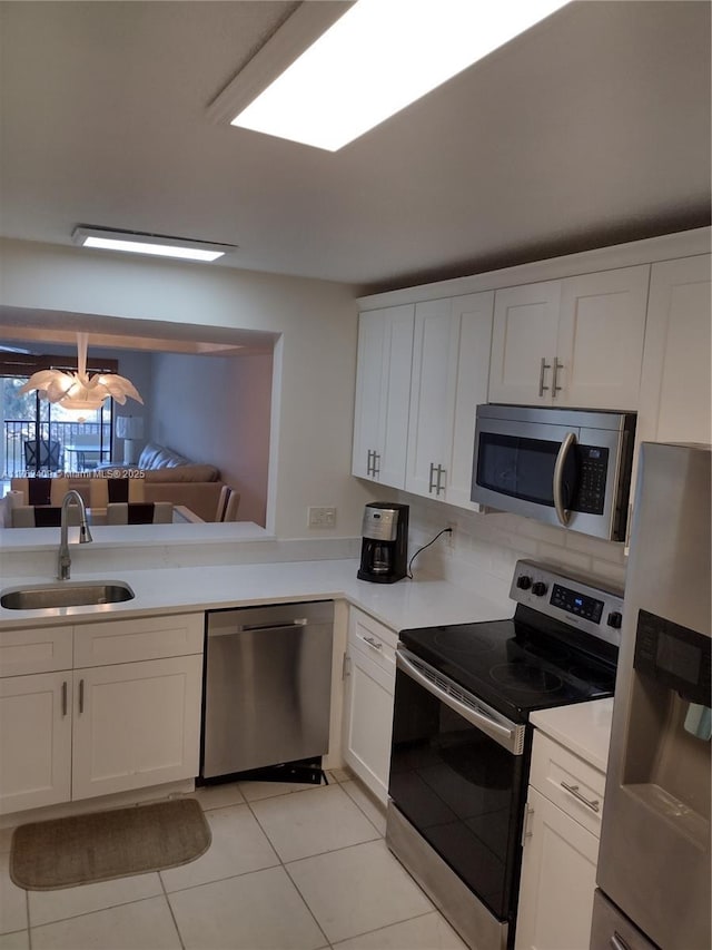 kitchen with a sink, white cabinets, light tile patterned flooring, and stainless steel appliances