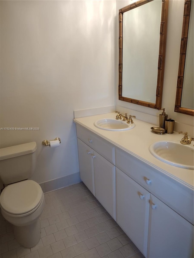 bathroom featuring double vanity, toilet, and a sink