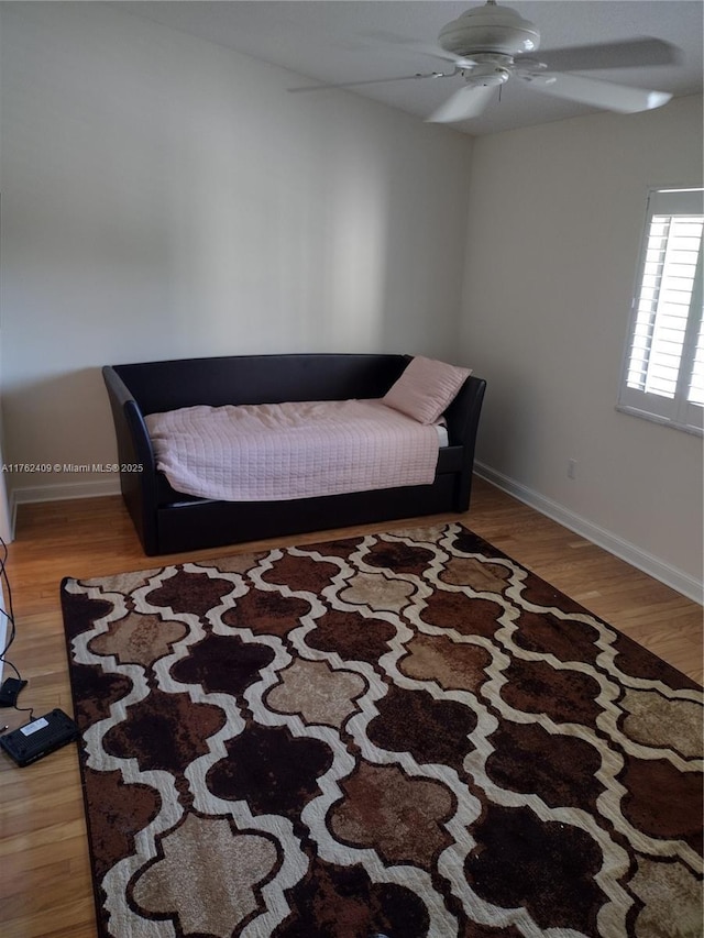 living area featuring ceiling fan, baseboards, and wood finished floors