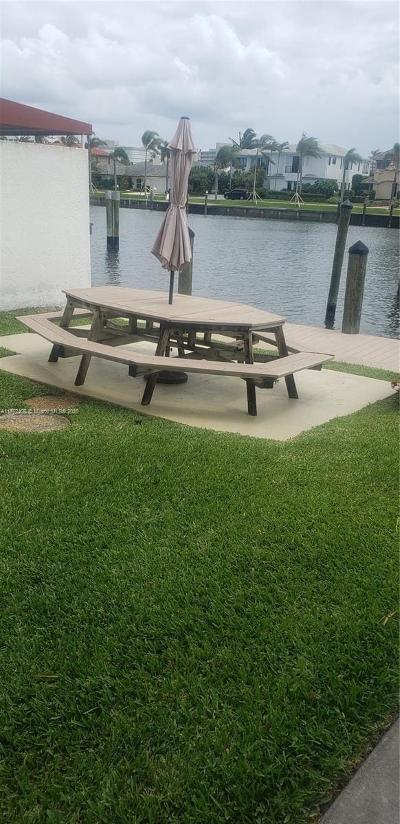 view of dock with a lawn, a water view, and boat lift