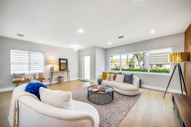 living room with light wood-type flooring, visible vents, baseboards, and recessed lighting