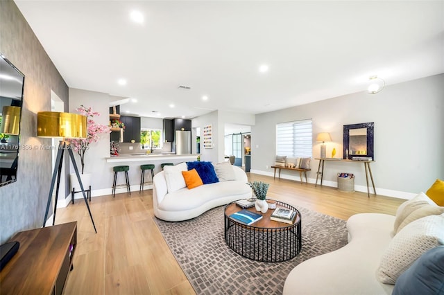 living area featuring recessed lighting, visible vents, light wood finished floors, and baseboards