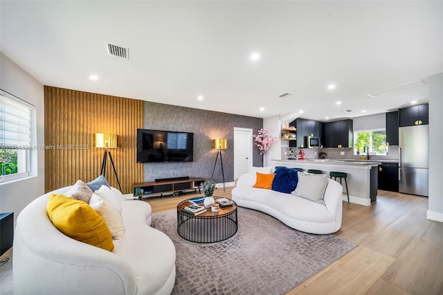 living room with visible vents, light wood finished floors, recessed lighting, wallpapered walls, and an accent wall