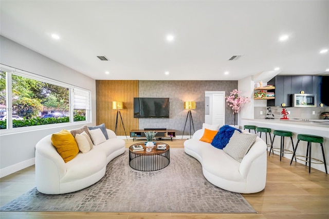 living area featuring wallpapered walls, recessed lighting, light wood-type flooring, and baseboards