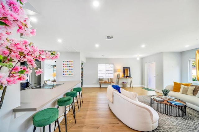 living room with light wood finished floors, visible vents, recessed lighting, and baseboards