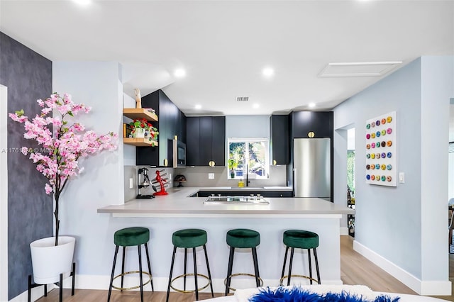 kitchen featuring visible vents, stainless steel fridge, light countertops, and dark cabinets